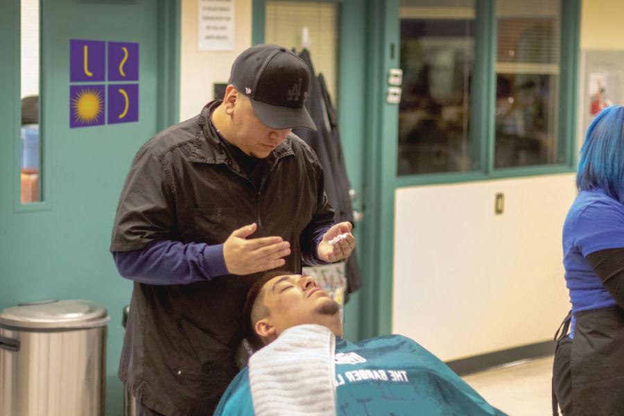 A 火博体育 student preparing to put shaving cream on a man's face before a shave