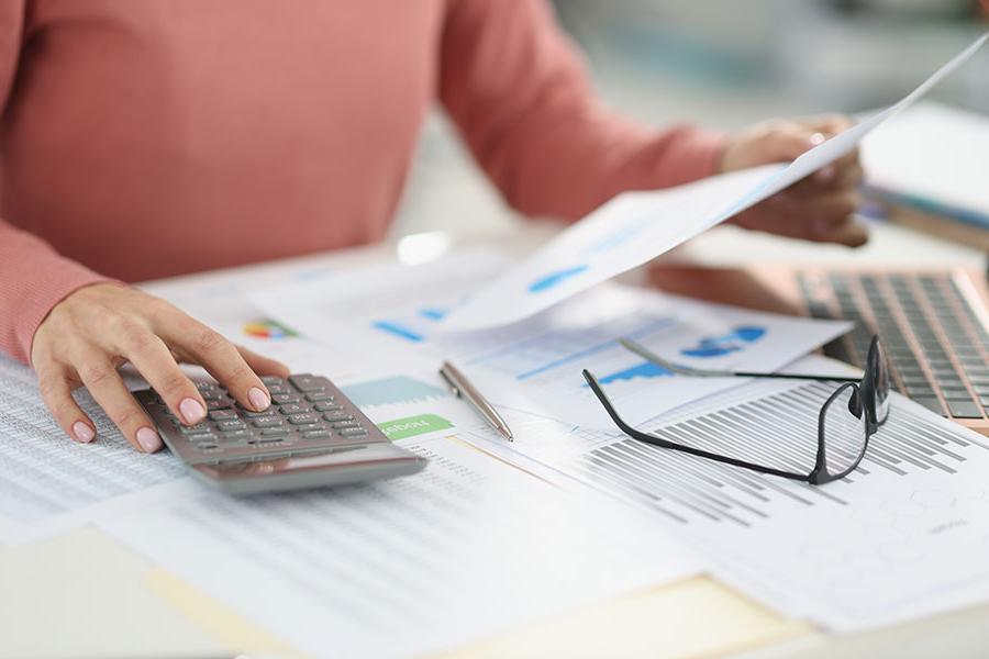 A 火博体育 student using a calculator to check numbers on printed accounting charts